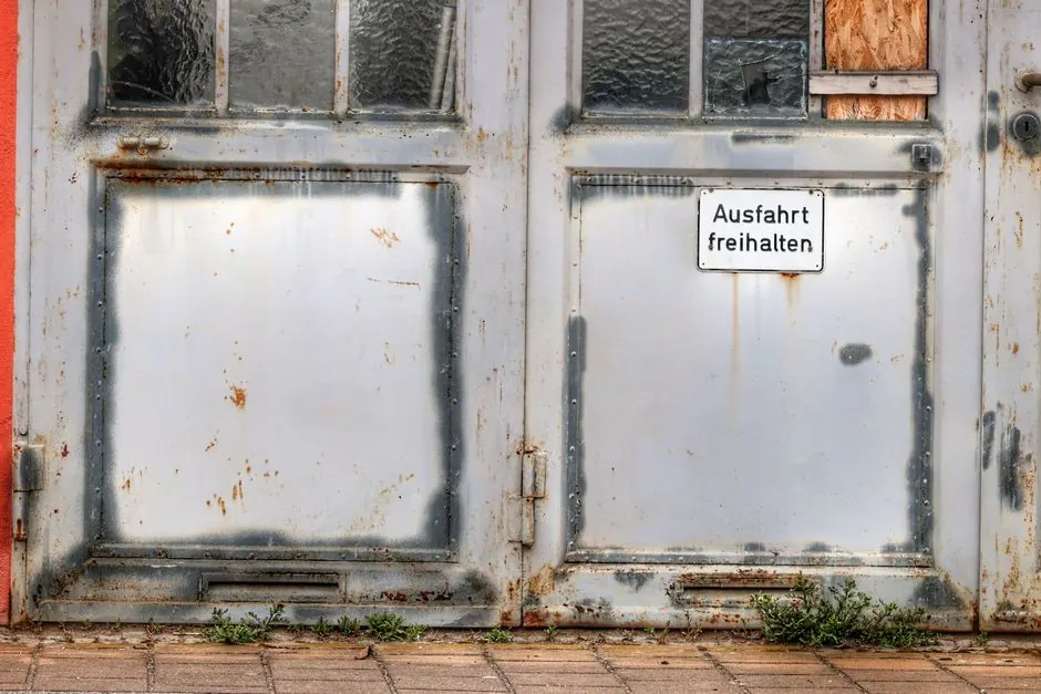Weathered garage door with a German sign reading 'Keep Exit Clear.'